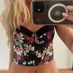 Blommig svart korsett topp - Supersöt korsett topp med blommor. Från Lindex, i storlek S. Superbra skick, pris kan diskuteras❤️