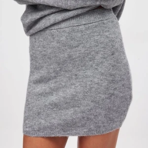 Grå stickad kortkjol - Mysig grå stickad kortkjol med enkel och clean design. Kjolen har en mjuk känsla och passar perfekt till en oversized tröja eller hoodie. Den är rak i modellen. Helt ny och oanvänd med prislapp 