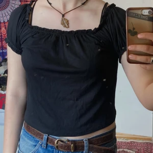 Svart croppad off shoulder topp från Gina Tricot, M - Svart croppad topp offshoulder från Gina Tricot med korta puffärmar och resår vid halsringning och ärmslut. Toppen kan bäras både offshoulder och med ärmarna uppe. Tunnt material och skön att ha på sommaren!
