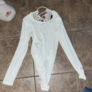 Vit spetsbody från Bik Bok XS - Supersnygg vit body från Bik Bok i storlek XS. Långärmad med detaljerad spets och snörning framtill samt vid halsen. Tight passform och mjukt material som känns skönt mot huden. Perfekt att styla med jeans eller kjol för en trendig look.