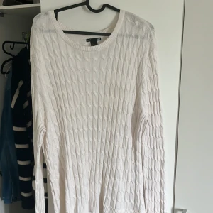 Vit kabelstickad tröja från H&M - Säljer en vit kabelstickad tröja från H&M med rund halsringning och långa ärmar. Tröjan har ribbade muddar vid ärmslut och nederkant samt en liten slits i sidan. Perfekt för lager-på-lager och enkel att matcha.