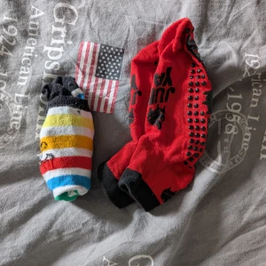 Färgglada randiga och röda halksockor M - Två par coola strumpor, Yamp yard i storlek M men det andra paret är barn storlek, står inte. Ena paret är randiga i svart, vit, gul, orange, röd och blå med siluettmotiv. Det andra paret är röda med svarta detaljer och halkskydd under foten. Perfekta för att chilla hemma eller springa runt inomhus. 