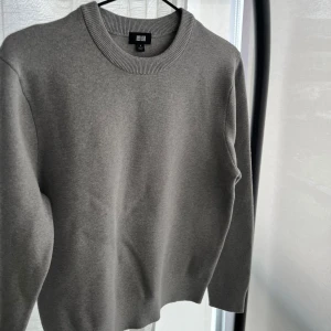 Grå stickad tröja från Uniqlo - Säljer en stilren grå stickad tröja från Uniqlo. Tröjan har rund halsringning och långa ärmar med ribbade muddar. Perfekt för lager-på-lager och enkel att matcha med olika outfits. Storlek är S men skulle påstå att den hade passat lika bra med XS.
