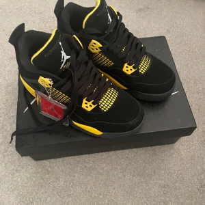 Nike Air Jordan 4 Retro SE svart/gul - Säljer ett par Nike Air Jordan 4 Retro SE i svart och gul med klassisk mesh och detaljer i gult. Skorna har snörning, platt sula och ikonisk Jumpman-logga på tungan och sulan. Perfekta för dig som vill sticka ut med en färgstark sneaker.