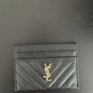 Korthållare i svart läder – klassisk & praktisk - Säljer en stilren korthållare i svart skinn med diskret och elegant design. Använd ett fåtal gånger – i mycket gott skick.  Svart läder av hög kvalitet Kompakt och lätt – får plats i fickan eller väskan Diskret logga framtill Mindre spår av normalt bruk – inga skador  Originalförpackning eller kvitto finns inte kvar. Bud är bindande – vänligen läs beskrivningen noggrant innan du lägger bud. Skickas spårbart inom 1–2 arbetsdagar efter betalning.