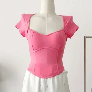 Rosa korsett crop-top - Säljer en rosa croppad topp med korta ärmar och snygg sweetheart-urringning. Den är väldigt sparsamt använd. Toppen har figurnära passform och markerade sömmar som ger en korsettliknande look. Lapp saknas men passar nog någon som bär XS/S. Det finns även plats att stoppa in paddings så man kan ha utan BH