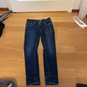 Levi's 512 Slim Taper jeans - Säljer ett par klassiska blå Levi's 512 Slim Taper jeans med snygg tvätt och smal passform. Byxorna har fem fickor, dragkedja och knapp framtill samt Levi's ikoniska läderpatch bak imidjan. lite trasig den där knappen där bak 