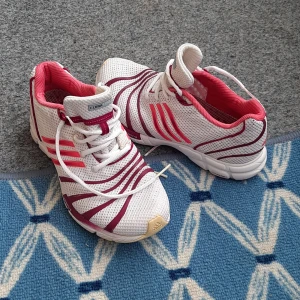 Adidas ClimaCool vita och vinröda sneakers - Snygga Adidas ClimaCool sneakers i vitt mesh med vinröda och rosa detaljer. Skorna har klassiska tre ränder på sidan, snörning och ventilerande material. Insidan är fodrad i rosa och sulan har coola detaljer i vinrött och beige. Perfekta för dig som gillar sportig stil.