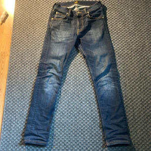 Mörkblå jeans från Lee - Säljer ett par mörkblå jeans från Lee med klassiska gula sömmar och fem fickor. Det är en slim modell som passar för 160-168 cm lång. Köpt för 900 och är som ny. Pris kan diskuteras!