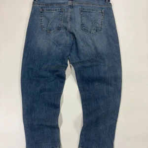 Blå jeans från Calvin Klein Jeans - Klassiska blå jeans från Calvin Klein Jeans med femficksdesign och raka ben. Jeansen har normal passform och subtila slitningar för en avslappnad look. Perfekta för dig som gillar en tidlös stil.