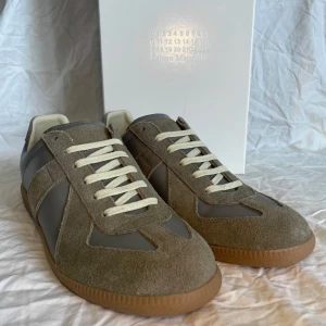 Maison Margiela skor grå/gröna - Säljer ett par Maison Margiela skor med grå/grön färg i nytt skick. Storlek 41 men passar även 42 och grym kvalité! Boxen och dustbags ingår.