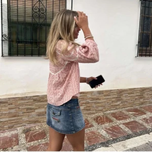 Rosa blus - Superfin rosa blus med vitt blommigt mönster och avslappnad passform. Blusen har långa ärmar med lätt puff och v-ringning framtill. Perfekt till jeans eller kjol för en chill och snygg look.