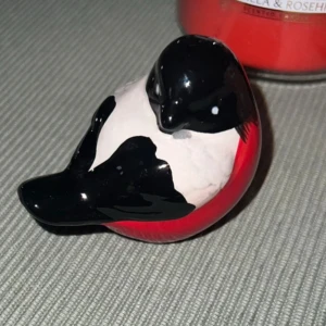 Fin fågel dekoration - En liten porslinsfågel med svart, vitt och rött mönster. Fågeln är detaljrikt målad och har ett hål undertill..