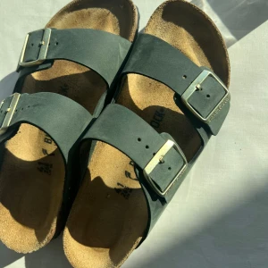 Gröna Birkenstock med guld spännen - Klassiska gröna Birkenstock sandaler. Modell Arizona. Perfekta för sommaren och riktigt sköna att gå i. Använda en gång! Nypris 1299kr 