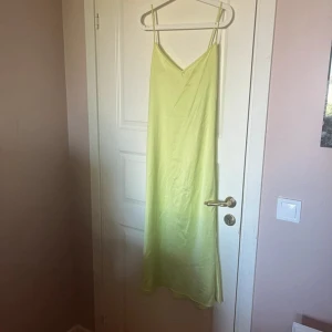 Ljusgrön långklänning med smala axelband - Säljer en ljusgrön långklänning med smala axelband och v-ringning. Klänningen har en enkel, rak passform och är tillverkad i ett mjukt, lätt material som faller snyggt. Perfekt för varma dagar eller sommarens alla tillfällen.