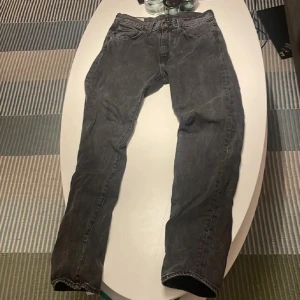 Levi's 502 svarta jeans W28 L32 - Säljer ett par svarta Levi's 502 jeans med klassisk femficksdesign och raka ben. Jeansen har en snygg tvättad look och är tillverkade i slitstarkt bomullsjeans. 