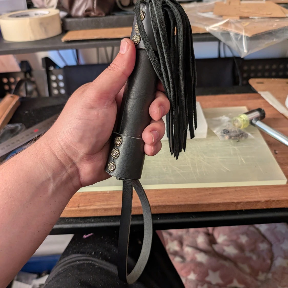 Svart läderpiska med nitar och fransar