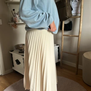 Plisserad beige långkjol från Gina Tricot - Säljer en superfin plisserad långkjol i beige med elastisk midja. Kjolen har ett snyggt fall och passar perfekt till en avslappnad eller mer uppklädd stil. Materialet känns lätt och flowy, perfekt för vår och sommar. Kommer från Gina Tricot.
