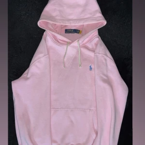 Ljusrosa hoodie från Polo Ralph Lauren - Säljer en ljusrosa hoodie från Polo Ralph Lauren med klassisk broderad logga i blått på bröstet. Tröjan har huva med snörning, känguruficka och är tillverkad i mjuk bomull. Perfekt för dig som gillar en clean och stilren look. Nypris 2195. Pris kan diskuteras. Storlek S kan passa M också.