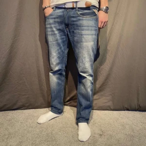 Blå jeans från Replay - Snygga blå jeans från Replay med en klassisk femficksdesign och subtila slitningar. De har en normal passform och är perfekta för en avslappnad stil. Märkesdetaljer syns vid fickan.