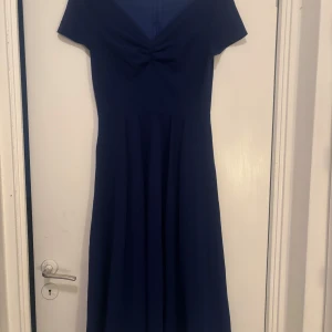 Marinblå klänning med knyt - Säljer en elegant marinblå klänning med korta ärmar och en vacker knytning framtill. Perfekt för en stilren look. Klänningen har en smickrande passform och är gjord i ett mjukt material. Klänningen är från shein i storlek S