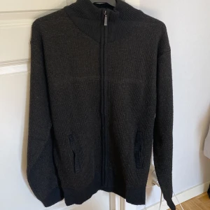 Mörkgrå stickad tröja med dragkedja från Kragbite - Säljer en mörkgrå stickad tröja från Kragbite med dragkedja framtill. Tröjan har en hög krage och långa ärmar, perfekt för kyliga dagar. Den har också praktiska fickor på sidorna. Perfekt för en stilren och bekväm look. passar inte priset kom gärna med pris förslag😁