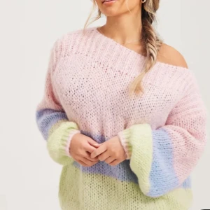 Flerfärgad stickad tröja - Mysig stickad tröja i pastellfärger med breda ränder i rosa, blått och grönt. Tröjan har en offshoulder-design och långa ärmar, perfekt för en avslappnad stil.