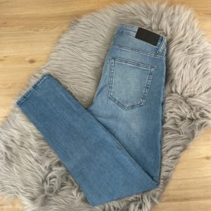 Blå jeans från Dressmann - Säljer ett par snygga blå jeans från Dressmann i slim fit. De har en klassisk femficksdesign och är perfekta för en stilren look. Midjan är midwaist och materialet är bekvämt och slitstarkt.