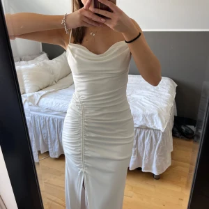 Vit långklänning med slits - Jättefin klänning från zara med draperad design och slits framtill, med tunna band upp till. Perfekt till studentmottagning eller skolavslutning🤩☺️ (den är endast använd en gång). 