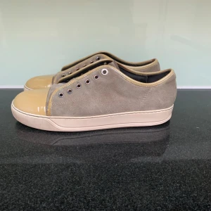 Beige sneakers från Lanvin - Snygga sneakers från Lanvin i en stilren beige färg. Skorna har en kombination av mocka och skinn med en rund tå och snörning. Perfekta för en avslappnad men ändå elegant look. Kommer med vita skosnören skriv om man vill ha bild. Uk 8 41-42. Snören kommer med. Dustbag kommer med. Skick 8-10✅ Ny pris 4800kr Vårat 1499kr