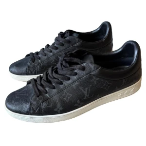 Svarta sneakers från Louis Vuitton - Snygga svarta sneakers från Louis Vuitton med monogrammönster. Skorna har en rund tå och snörning, vilket ger en klassisk look. Perfekta för dig som vill ha stil och komfort i ett. Äktenhetsbevis finns, sjukt bra skick