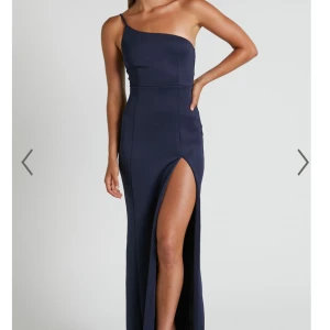 Mörkblå långklänning med slits - Elegant mörkblå långklänning med en stilren oneshoulder-design och hög slits. Perfekt bröllop eller annat. Jag är 163 cm och vanlig xs. Klack 11 cm på bild, använd en kväll, så gott som ny.