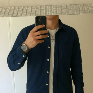 Blå skjorta från GANT - Säljer en stilren blå skjorta från GANT med klassisk krage och knappar framtill. Skjortan har en bröstficka och är långärmad, perfekt för en elegant look.