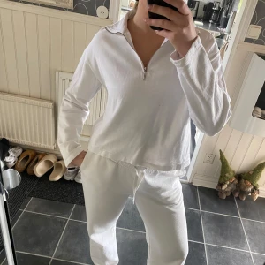 Vit långärmad tröja med dragkedja - Säljer en vit långärmad tröja med dragkedja i halsen. Tröjan har en avslappnad passform och är perfekt för en bekväm stil. Passar bra till både jeans och mjukisbyxor.