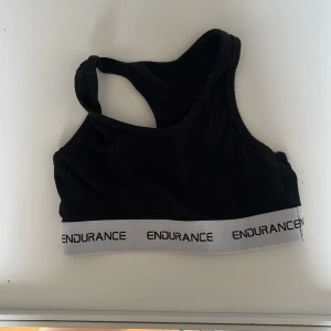 Svart sporttopp från Endurance - Säljer en svart sporttopp från Endurance med vit resårkant och logga. Perfekt för träning med sin bekväma passform och stilrena design.