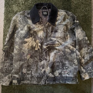 Camouflage jacka från BDG Urban Outfitters  - Säljer en cool camouflage jacka från BDG med dragkedja och krage i manchester. Jackan har långa ärmar och två fickor framtill. Säljer pga fel storlek.