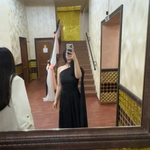 Svart oneshoulder klänning - Elegant svart oneshoulder klänning med lång design. Perfekt för en stilren och sofistikerad look. Klänningen har en flytande passform som ger en vacker siluett. 