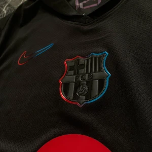 Svart fotbollströja från Nike - Snygg svart fotbollströja med klubbmärke och Nike-logga i rött och blått. Helt ny den passade bara inte mig 