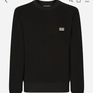 Svart tröja från Dolce & Gabbana - Snygg svart tröja från Dolce & Gabbana med en diskret logotyp på bröstet. Tröjan har en klassisk rund hals och långa ärmar, perfekt för en stilren look. Ribbstickade muddar vid ärmslut och nederkant ger en bekväm passform.                      Alldrig använd fick i födelsedagspresent men var för liten passar storlek s. Har tyvär inte några kvitton elle något. Säljer Drf för 4000kr.
