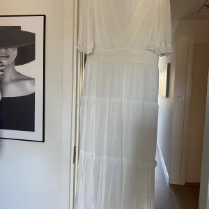 Vit långklänning från Dobber Stl M - Elegant vit långklänning med v-ringning och spetsdetaljer. Klänningen har korta ärmar och ett fint fall. Perfekt för sommarens festligheter. Helt ny, bara provat. Säljes för den är förlång för mig. Jag är 159cm Pris. 600kr Ord ca 900kr
