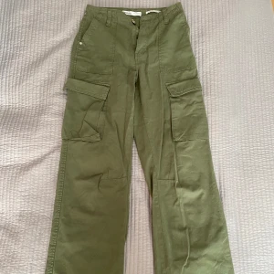 Olivgröna cargobyxor från Bershka - Säljer ett par olivgröna cargobyxor från Bershka. Byxorna har en rak passform med flera praktiska fickor och en medelhög midja. Perfekta för en avslappnad stil.