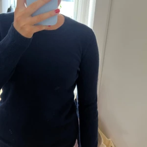 Mörkblå kashmirtröja från From Future - Säljer en elegant mörkblå kashmirtröja från From Future. Tröjan har en klassisk design med långa ärmar och rund halsringning. Perfekt för att hålla sig varm och stilren under kyligare dagar. Använd ett fåtal gånger så i väldigt bra skick!