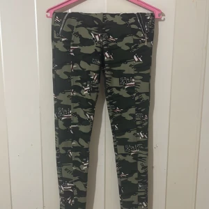Camouflage leggings med amerikanska flaggor - Snygga leggings med ett coolt camouflage-mönster och amerikanska flaggor. Perfekta för en avslappnad stil med en twist. De har en tight passform och är gjorda i ett stretchigt material för extra komfort.