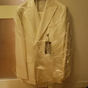 Vit kavaj från Oscar Jacobson - Elegant vit kavaj från Oscar Jacobson med klassisk design. Helt nya aldrig använd! Passar perfekt till bal och bröllop. Nypris ligger på 9999kr! Mitt pris 3399!