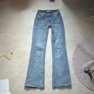 Ljusblå bootcut jeans från Madlady - Ljusblå jeans med bootcut passform från Madlady. Låg midja med dubbla knappar framtill, stora framfickor och bakfickor med lock och knapp. Short EU32 passar mig som är 158. Skriv för fler bilder och pris kan diskuteras. Oanvända endast testade. Nypris 699kr💓