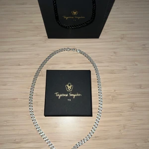 Silver kedjehalsband från Tayrona Smycken - Stilrent halsband i äkta silver från Tayrona Smycken. Kedjan har breda, platta länkar som ger ett modernt och trendigt intryck. Perfekt accessoar för att lyfta din outfit.