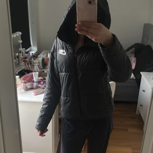 Svart pufferjacka  - Säljer en svart pufferjacka från Nike då den inte kommit till användning. Jackan har lång ärm och är perfekt för kyligare dagar. Klassisk logga på bröstet och vid midjan är en enkel, sportig design.
