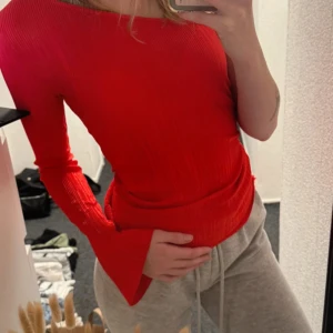 Röd ribbad omlottopp från Gina Tricot - Säljer en snygg röd ribbad omlottopp från Gina Tricot. Tröjan har lång ärm, v-ringning och en omlottdesign som ger en cool asymmetrisk look. Perfekt för dig som vill sticka ut med färg och form!