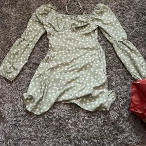 Grön blommig klänning  - Söt grön klänning med vita små blommor🌼Klänningen har en lätt rynkad byst och smickrande passform. Perfekt för vår och sommar, med en romantisk och trendig känsla.