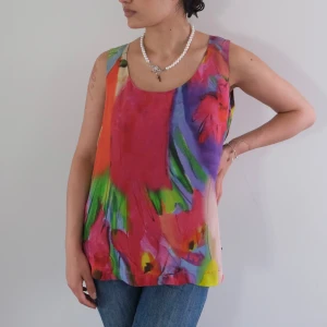 Vintage Iceberg topp - Vintage Iceberg topp   Färgglad ärmlös topp med ett abstrakt blommönster i livliga nyanser av rosa, lila, orange, grönt och blått. Toppen har en rund halsringning och en lätt A-linjeform.  Storlek S   Length: 61cm Chest:42cm